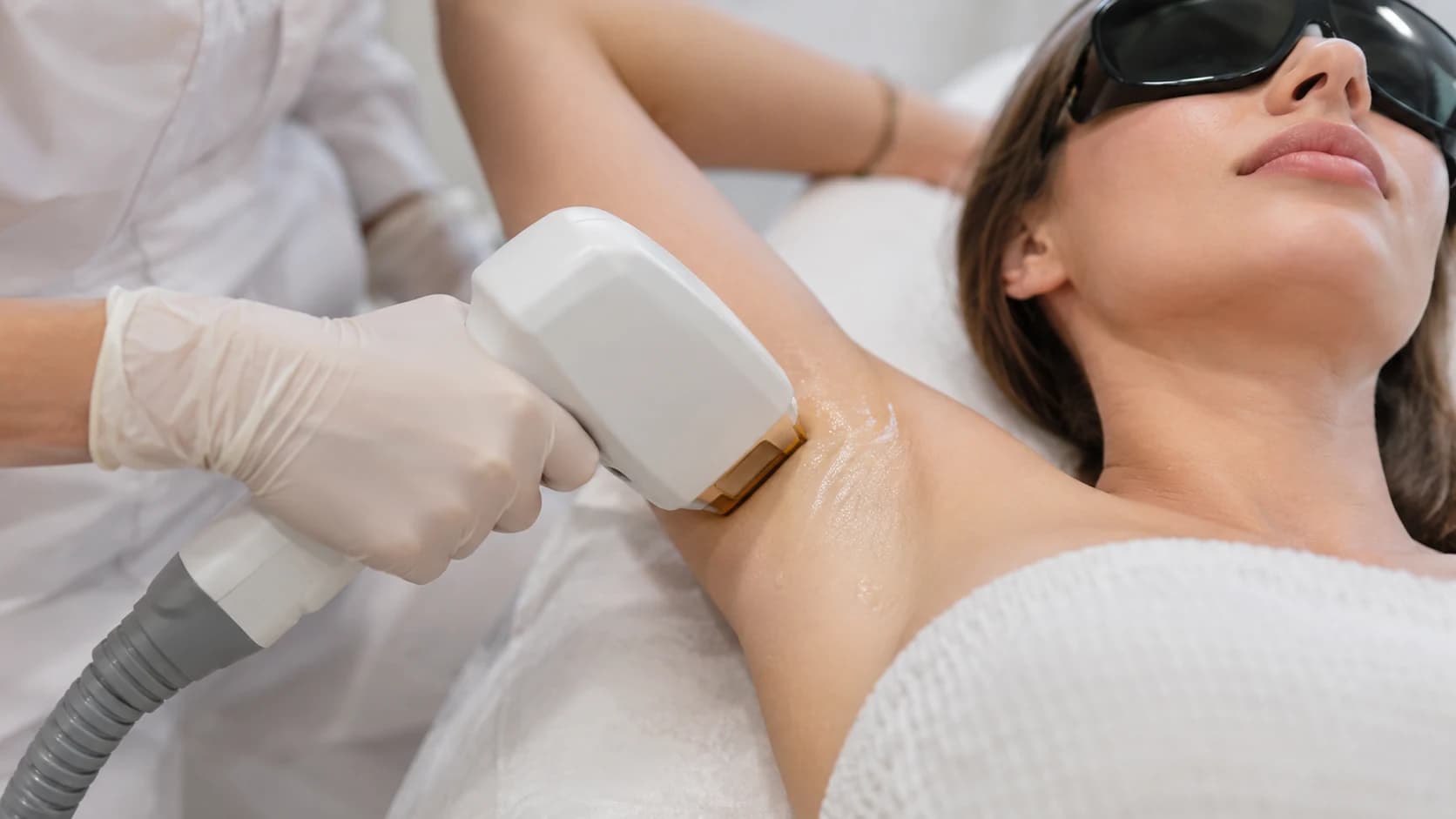 Laserontharing van een oksel met behandelkop, gehandschoende handen en beschermbril